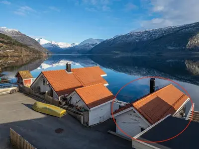 a house with orange roofs on a lake with mountains at Stryn Fjord Cottage Faleide in Stryn