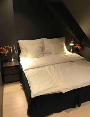 a bedroom with a large bed with white sheets and pillows at City Centrum Villa Apartments w parking in Bergen