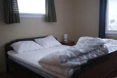 an unmade bed in a bedroom with a window at Nesheim in Alnes