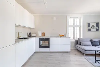 a white kitchen with white cabinets and a couch at Skuteviken House in Bergen