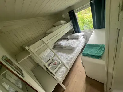 a bunk bed in a small room with a window at #Beautiful outdoor area and cozy small cottage# in Fotlandsvåg