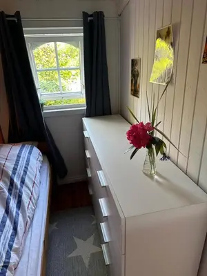 a bedroom with a dresser with a vase of flowers on it at #Beautiful outdoor area and cozy small cottage# in Fotlandsvåg