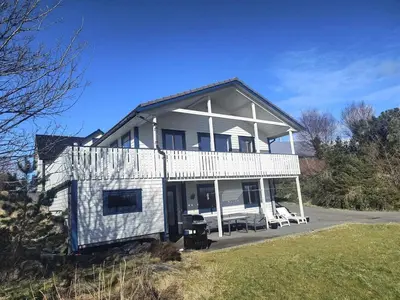 a large white house with two white chairs in a yard at Skjærgårdsidyll in Askøy