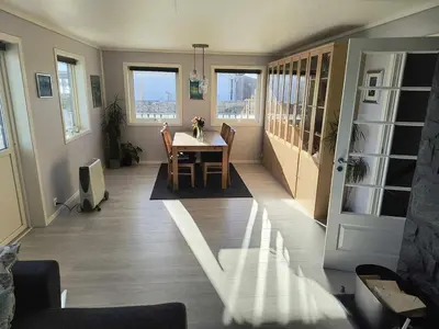 a dining room with a table and chairs and windows at Skjærgårdsidyll in Askøy
