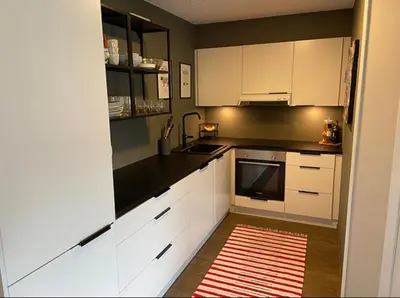 a kitchen with white cabinets and a red rug at 2 Bedroom Apartment with free parking lot in Bergen