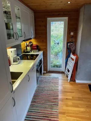 a kitchen with white cabinets and a door to a yard at Flott familiehytte på Haukås i Strandebarm in Kvam