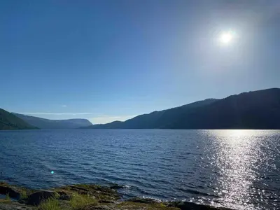 a large body of water with the sun in the sky at Perla i Nordfjord in Emhjella