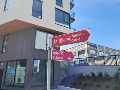 two street signs on a pole in front of a building at New apartment 5min to airport at Kokstad train station in Bergen