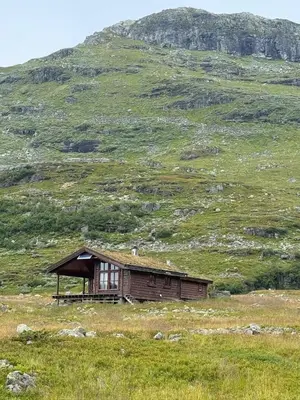 an old cabin in a field with a hill at Wild Norwegian nature, between Preikestolen & Trolltunga in Sauda
