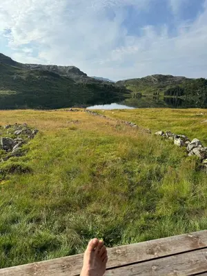 a persons foot sitting on a bench in a field at Wild Norwegian nature, between Preikestolen & Trolltunga in Sauda