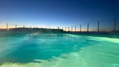 a swimming pool with blue water and a fence at Villa with heated pool and magnificent view in Bergen