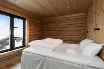 a bed in a wooden room with a window at Nordic Gateway Logde in Hafjell