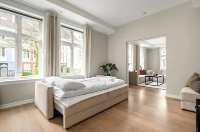 a white bedroom with a large bed and windows at Scandinavian Luxury in Bergen's Finest Street in Bergen