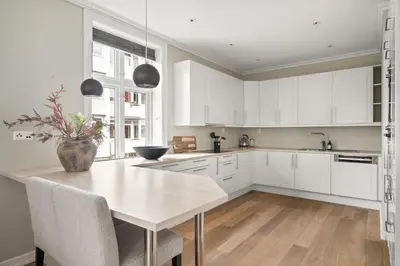a kitchen with white cabinets and a table with a vase on it at Scandinavian Luxury in Bergen's Finest Street in Bergen