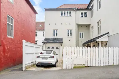 a white car parked in front of a white fence at Scandinavian Luxury in Bergen's Finest Street in Bergen