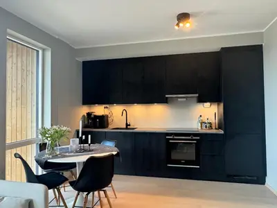 a kitchen with black cabinets and a table and chairs at Modern, brand-new apartment in the heart of Bergen in Bergen