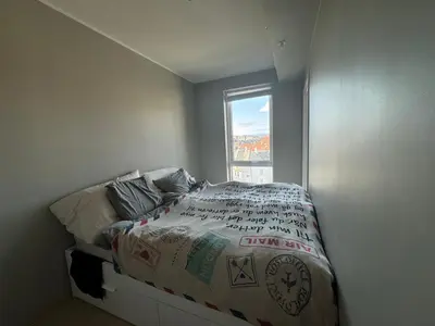 a small bedroom with a bed with a window at Modern, brand-new apartment in the heart of Bergen in Bergen
