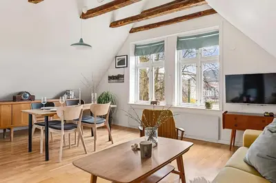 a living room with a table and chairs and a tv at Design Apartment by Bryggen - View & Location in Bergen