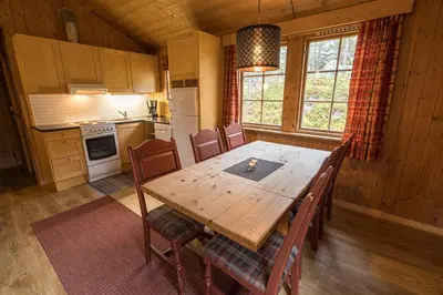 a kitchen and dining room with a wooden table and chairs at Lemonsjø Fjellstue og Hyttegrend in Randsverk