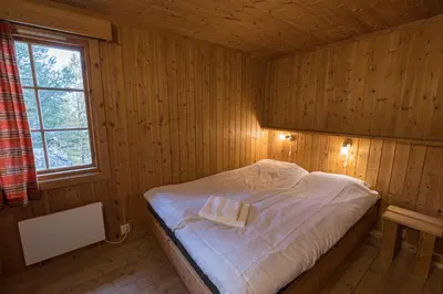 a bedroom with a bed in a wooden room at Lemonsjø Fjellstue og Hyttegrend in Randsverk