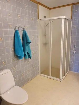 a bathroom with a shower and a toilet with blue tiles at Sandeidfjorden overnatting in Sandeid