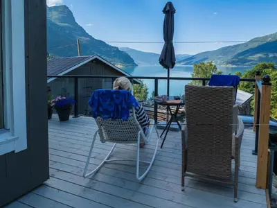 a child sitting in chairs on a deck with a table and an umbrella at Fjord Cabin with Panoramic View & Private Balcony in Luster