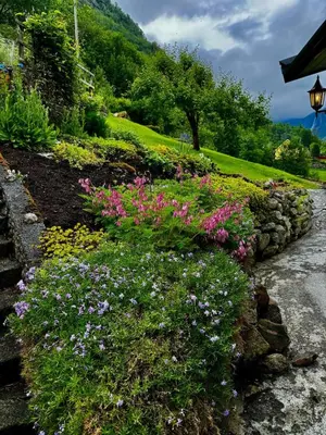 a garden with flowers and a stone wall at 4 bedroom house in beautiful Oldedalen in Stryn