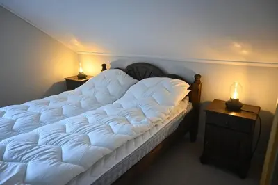 a large white bed in a room with two night stands at 4 bedroom house in beautiful Oldedalen in Stryn