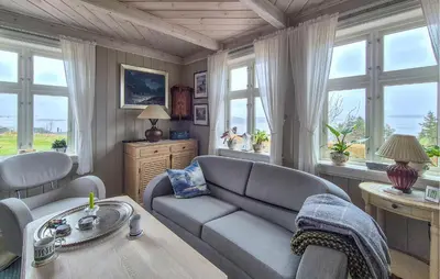 a living room with a couch and a table and windows at Awesome Home In Bekkjarvik in Bekkjarvik