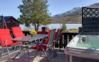 a table and chairs on a deck with a hot tub at Lovely Home In Straumgjerde in Brunstad