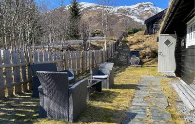 two chairs and a fence next to a house at Lovely Home In Straumgjerde in Brunstad