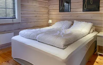 a large white bed in a room with a wooden wall at Lovely Home In Straumgjerde in Brunstad