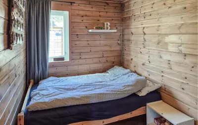 a bed in a room with wooden walls at 4 Bedroom Stunning Home In Hebnes in Hebnes