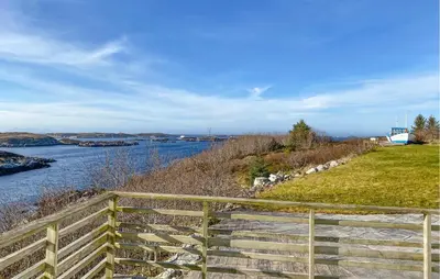 a wooden fence next to a river with a bridge at 5 Bedroom Beautiful Home In Kverva in Kverva