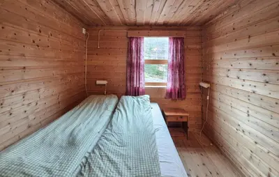 a bed in a log cabin with a window at Lovely Home In Masfjordnes With Sauna in Masfjorden