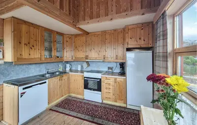a kitchen with white appliances and wooden cabinets at Lovely Home In Masfjordnes With Sauna in Masfjorden