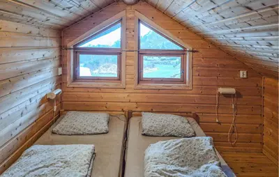 a room with two beds in a cabin with a window at Cozy Home In Masfjordnes With Sauna in Masfjorden