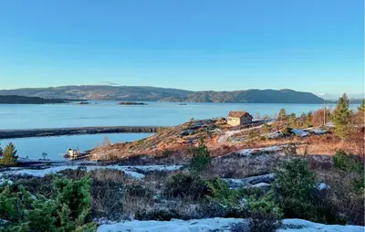 a house on a hill next to a body of water at Cozy Home In Masfjordnes With Sauna in Masfjorden