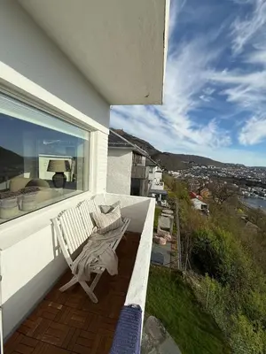 a white bench sitting on the balcony of a house at Apartment in Bergen in Bergen