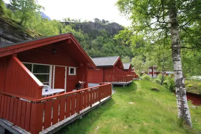 a row of red cottages in a forest at Vinje Camping in Geiranger