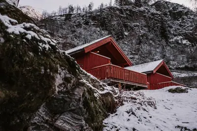 a red cabin with snow on the side of a mountain at Vinje Camping in Geiranger