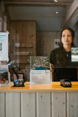 a woman standing behind a counter with a laptop at Vinje Camping in Geiranger