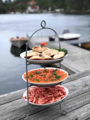 three plates of food on a table next to the water at Seaside Cabin with panoramic view in Bømlo