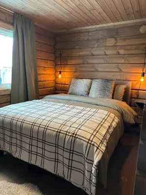 a bedroom with a bed with a wooden wall at Sentrumsnær Røroshytte in Røros