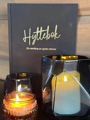 two candles are sitting on a table next to a box at Sentrumsnær Røroshytte in Røros
