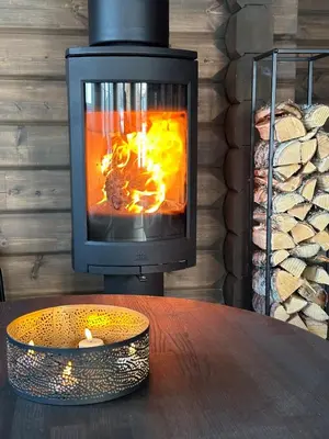 a wood stove with a fire in it at Sentrumsnær Røroshytte in Røros