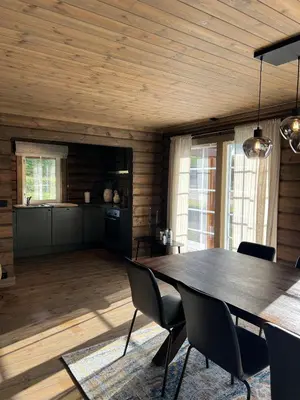 a dining room with a large wooden table and chairs at Sentrumsnær Røroshytte in Røros