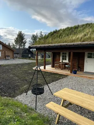 a tripod in front of a log cabin with a grass roof at Sentrumsnær Røroshytte in Røros