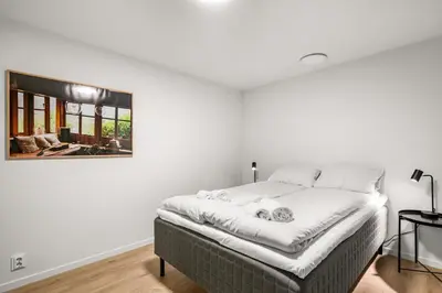 a white bedroom with a bed with a picture on the wall at Scandinavian Design in Authentic Nordnes in Bergen