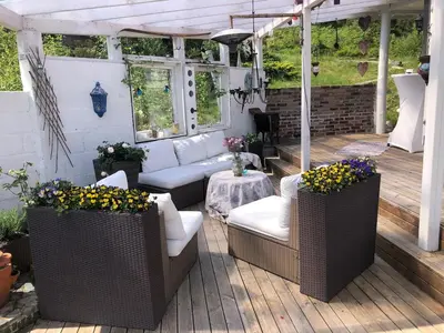 a patio with couches and a table with flowers at Stay where the mountains begin in Bømlo